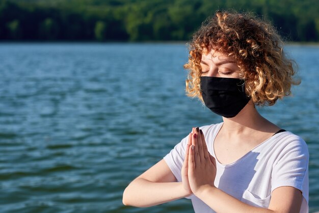 A young woman with curly hair doing yoga outside