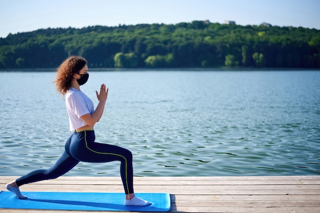 A young woman with curly hair doing yoga outside