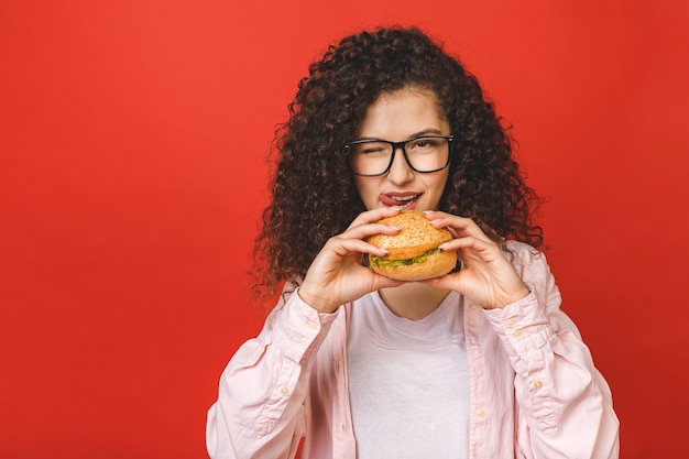 Young woman with curly hair holding hamburger