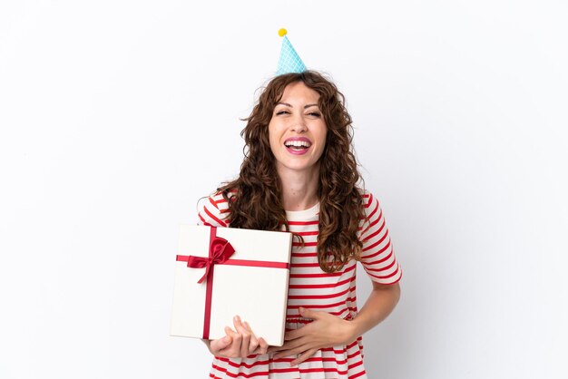 Giovane donna con capelli ricci che tiene presente isolato su sfondo bianco sorridente molto