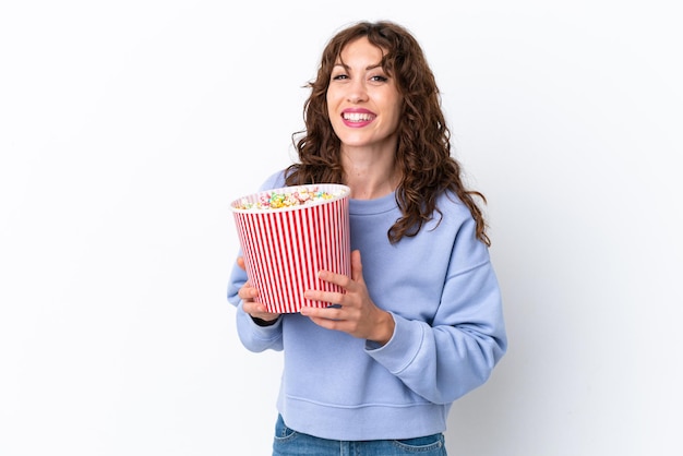 Young woman with curly hair isolated on white background holding a big bucket of popcorns