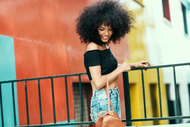 Photo young woman with curly hair near a modern colorful building