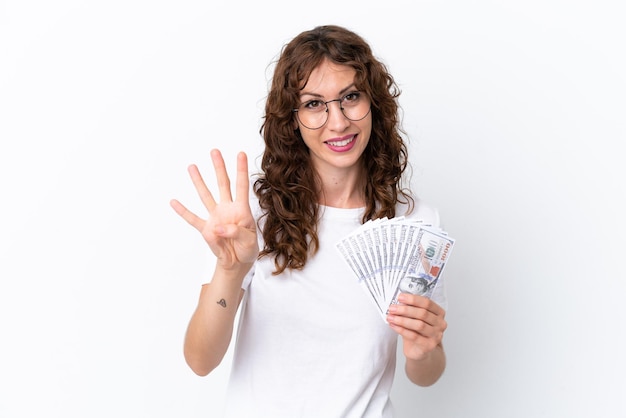 곱슬머리를 한 젊은 여성은 흰색 배경에 고립된 배경에서 많은 돈을 받고 행복하고 손가락으로 4를 세고 있습니다.