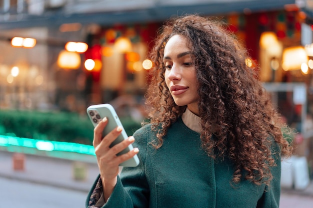 写真 街でスマートフォンを使っている巻きの若い女性