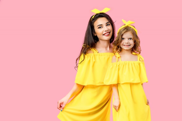 Young woman with cute child posing in yellow dresses