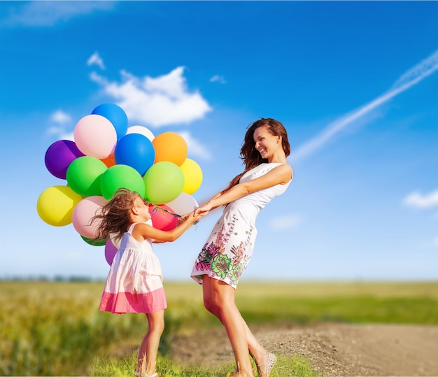 Young woman with cute little girl and colorful air balloons