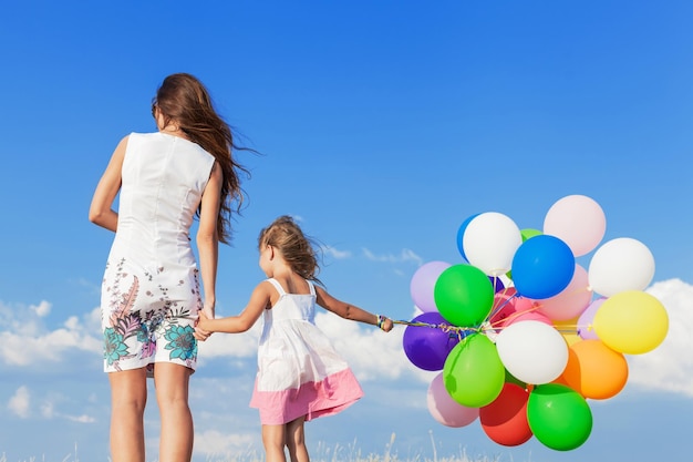 Young woman with cute little girl and colorful air balloons