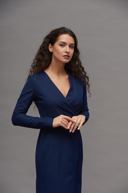 Young woman with dark long hair wearing smart blue dress during photo session