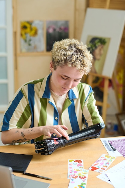 Young woman with disability sticking handmade stickers on her myoelectric arm