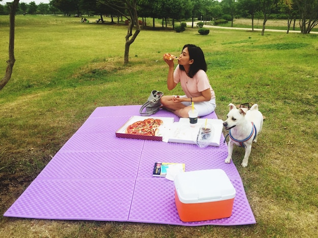 Young woman with dog sitting on field