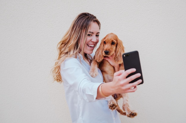 壁のそばに犬を連れて立っている若い女性