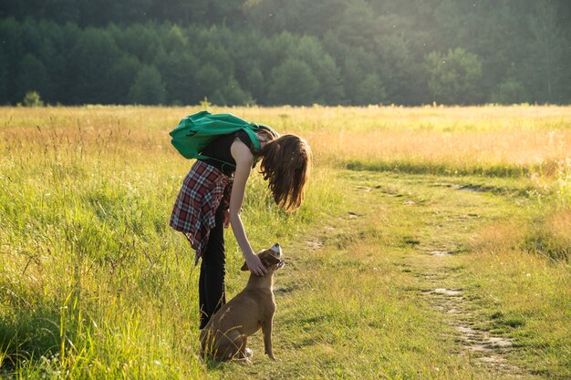 晴れた日にフィールドで散歩に犬を持つ若い女性