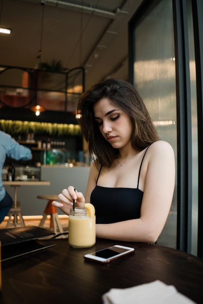 Young woman with drink sitting at restaurant table