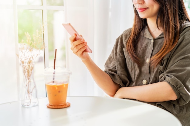 Photo young woman with drinks using mobile phone and relaxing in cafe modern lifestyle