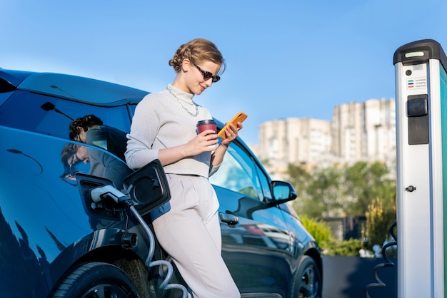 Giovane donna con un'auto elettrica alla stazione di ricarica a chisinau moldova