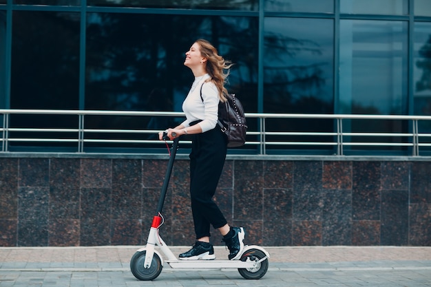 街で電動スクーターを持つ若い女性