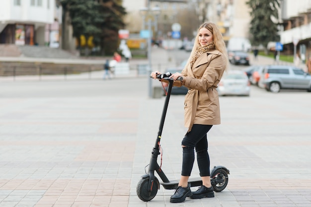 市内の電動スクーターを持つ若い女性