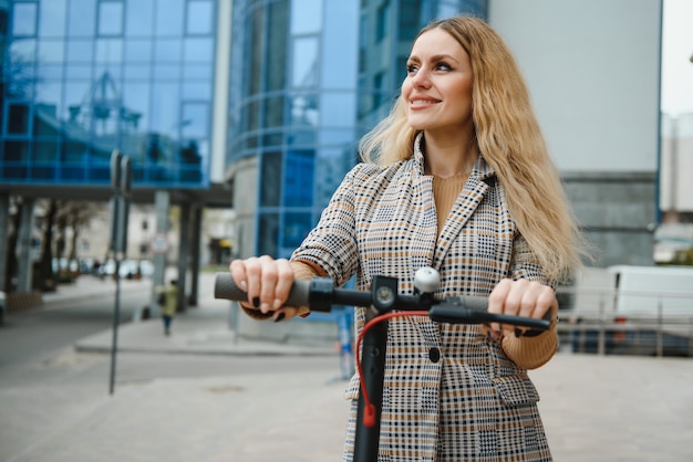 市内の電動スクーターを持つ若い女性