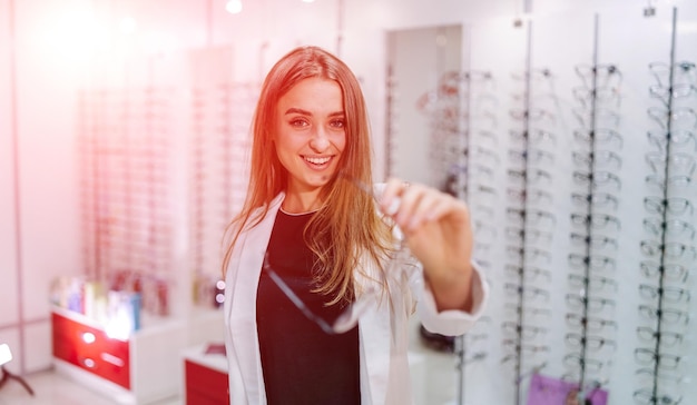 Young woman with eyeglasses in optical store beautiful girl\
wearing glasses in optician shop ophthalmology