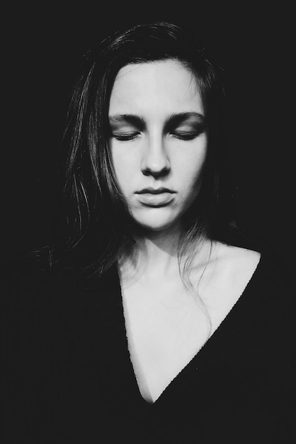 Young woman with eyes closed against black background