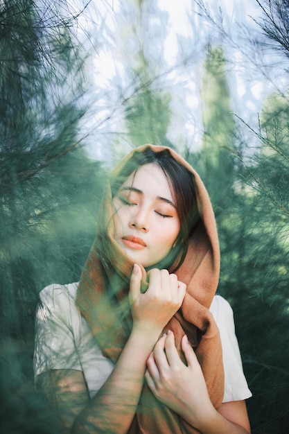 young woman with eyes closed against trees