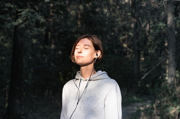 Young woman with eyes closed listening music in forest