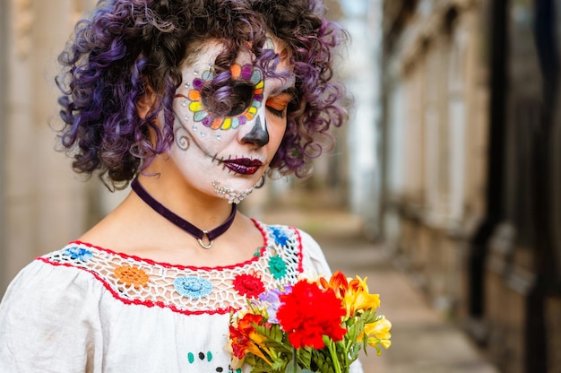 Young woman with eyes closed praying for the peace of her dead relatives with catrina makeup