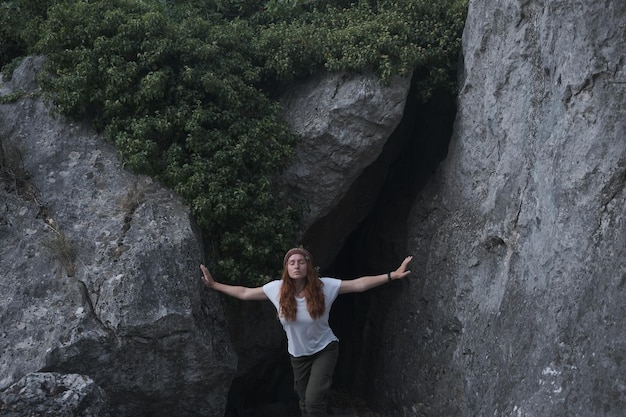 Foto giovane donna con gli occhi chiusi in piedi vicino alla grotta