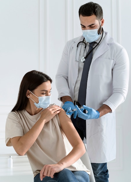 Foto giovane donna con maschera facciale vaccinata dal medico