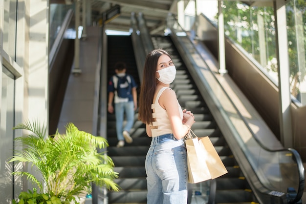 フェイスマスクを持つ若い女性は屋外市に立っています。