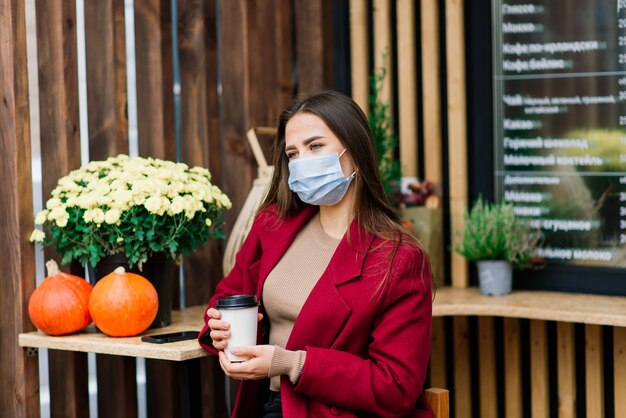 Giovane donna con una maschera facciale al ristorante, nuovo concetto normale per proteggere la pandemia di coronavirus