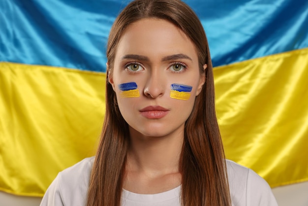 Young woman with face paint near Ukrainian flag