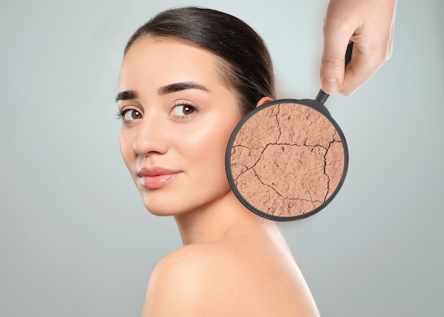 Young woman with facial dry skin problem on light grey background