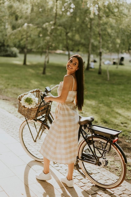 電動自転車のバスケットに花を持つ若い女性