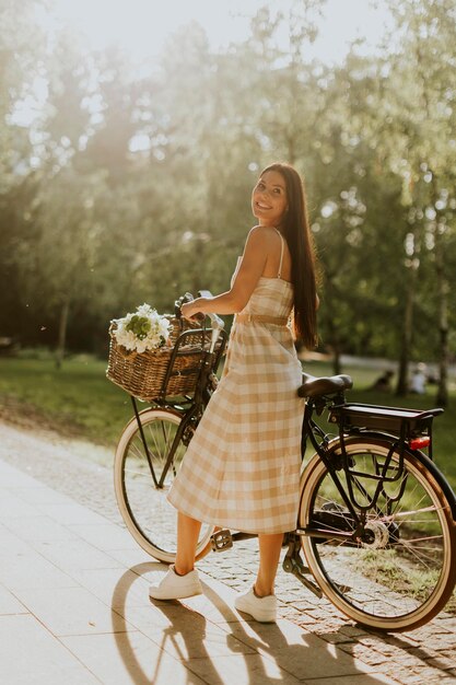 電動自転車のバスケットに花を持つ若い女性