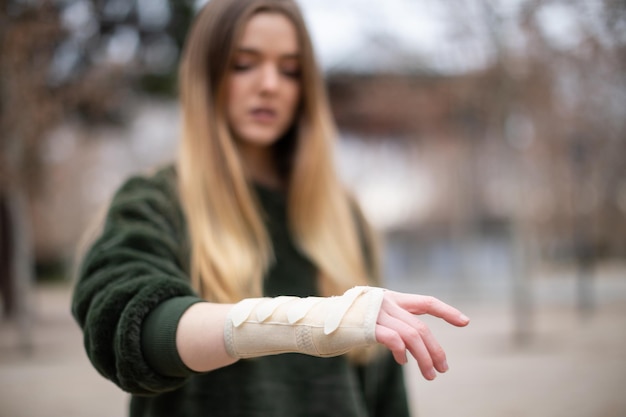 Young woman with fractured hand standing on street