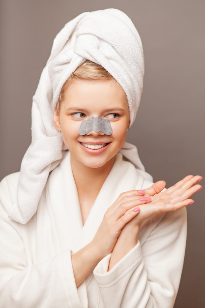 Young woman with fresh healthy skin and hairs aplying stripe from black dots.