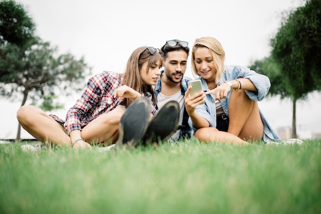 Foto giovane donna con gli amici che usano il telefono sul campo