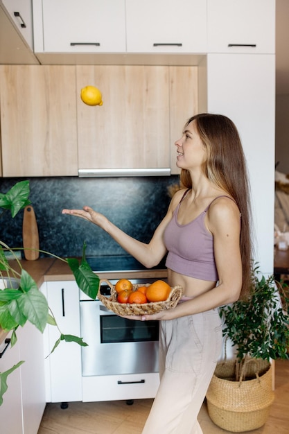 キッチンで果物を持つ若い女性自宅で健康的なビーガンフード