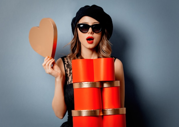 Young woman with gift boxes on grey wall