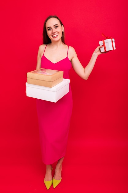 Young woman with gifts in her hands on a red background Christmas tradition of giving gifts