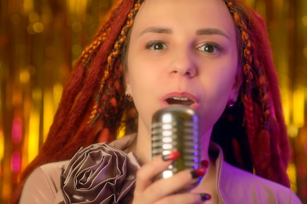 Young woman with ginger dreadlocks singing into microphone Portrait of female singer with microphone in studio