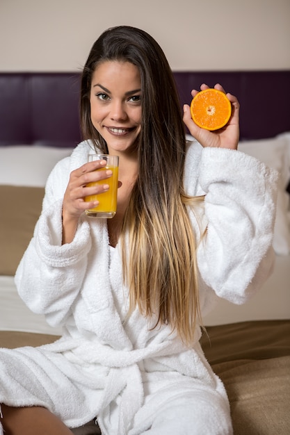 Young woman with glass of juice and orange