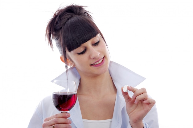 赤ワインと薬のグラスを持つ若い女性