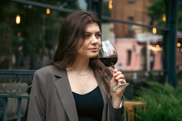 Una giovane donna con un bicchiere di vino fuori vicino a un ristorante