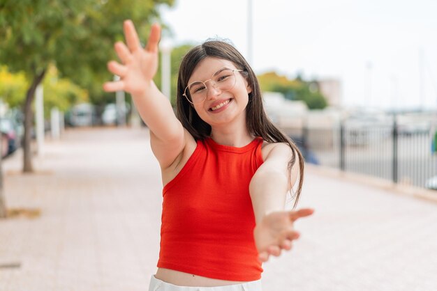 外で眼鏡をかけた若い女性が手を差し出して来るよう招待している