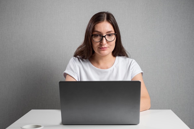 Young woman with glasses sits at a laptop