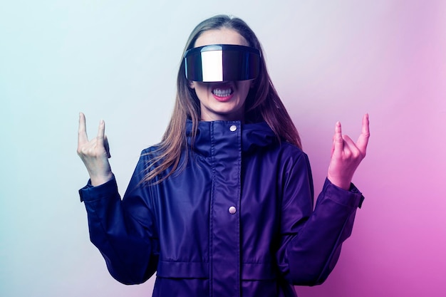 Young woman with glasses of virtual reality shows rocker goat added gradient on a light background