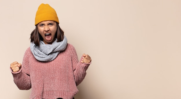 Young woman with a goofy, crazy, surprised expression, puffing cheeks, feeling stuffed, fat and full of food