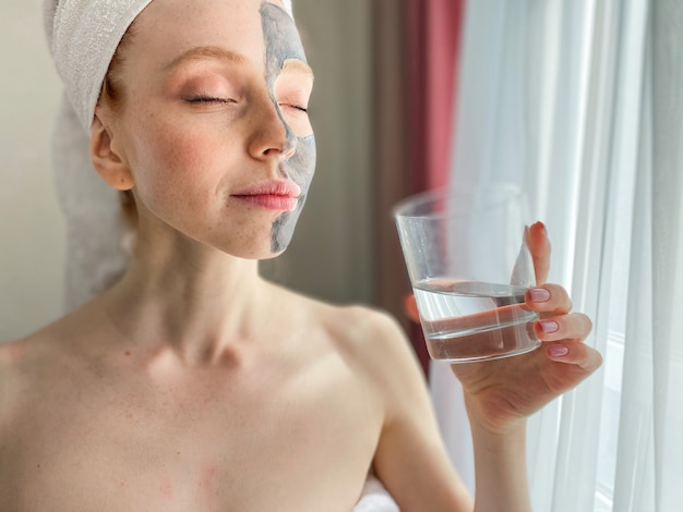 Foto giovane donna con una maschera di argilla grigia